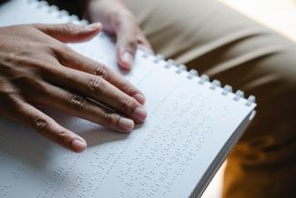 Eine blinde Person liest einen Text in Brailleschrift