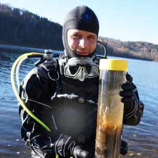 Wissenschaftlicher Taucher mit Ausrüstung und einer Unterwasser Sedimentprobe mit einem Süßwasserschwamm