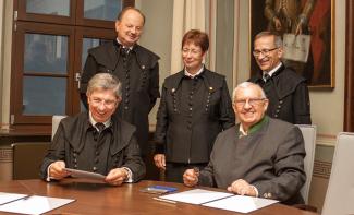 Ein Bild mit 5 Personen bei der Unterzeichnung eines Vertrags.