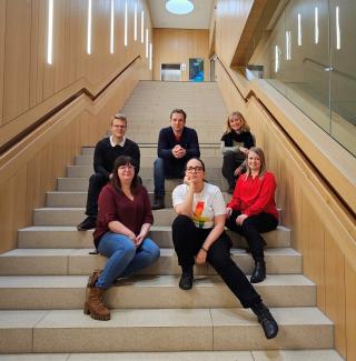 Das Team der Professur für Verhaltens- und Wirtschaftsethik sitzt auf der Treppe im Schlossplatzquartier