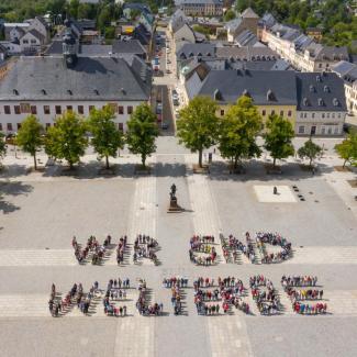 Menschen bilden einen "Wir sind Welterbe"-Schriftzug auf dem Marktplatz von Marienberg