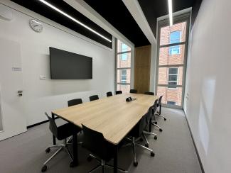 Gruppenarbeitsraum mit Tischen, Stühlen und Monitor an der Wand