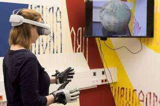 Mixed Reality Raum mit Mitarbeiterin, Bildschirm, 3D-Brille und grafischer Wand