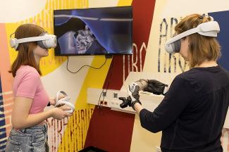 Mixed Reality Raum mit Mitarbeiterinnen, Bildschirm, 3D-Brillen und grafischer Wand
