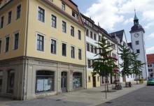 Ein gelbes Gebäude mit der Beschriftung Bürgerhaus Stadt Freiberg auf einem Marktplatz, rechts daneben in der gleichen Häuserzeile ein weißer Rathausturm