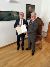 Der Rektor Prof. Klaus-Dieter Barbknecht und der neue Honorarprofessor Dr. Andreas Fichtner präsentieren die Bestellungsurkunge der TU Bergakademie Freiberg für Herrn Fichtner