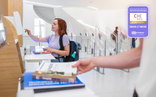 Studentin leiht ein Buch in der Bibliothek aus.