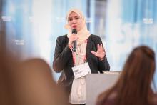 Eine Frau spricht vor einem Auditorium in ein Mikrofon.