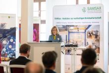 Eine Frau hinter einem Pult spricht während einer Festveranstaltung.