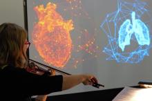 Geigerin spielt vor Leinwand, auf der ein Herz und eine Lunge visualiert sind.