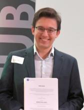 Ein Student im Anzug mit einer Urkunde