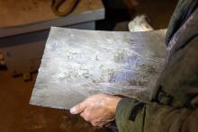 Stahlplatte nach der Sprengung: Während von Blüten, Blättern und Stängeln nichts mehr zu finden ist, tritt ihr detailscharfes Prägebild reliefartig hervor.