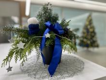 Bild zeigt einen Weihnachtsgesteck mit einer blauen Schleife und silbernen Sternen