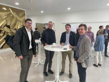 Personen stehen um Stehtische herum.