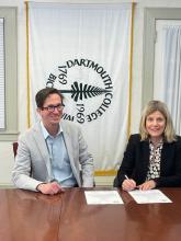 Zwei Personen, eine unterzeichnet einen Vertrag.