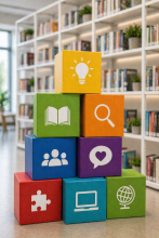 Ein Stapel bunter Würfelkartons mit weißen Symbolen wie Buch, Lupe, Glühbirne, Menschen, Puzzle, Computer und Globus steht pyramidenförmig im Vordergrund. Im Hintergrund ist unscharf ein Bücherregal mit zahlreichen Büchern zu sehen.