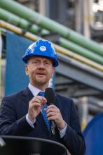 Ein Mann in Anzug und mit Helm hält eine Rede