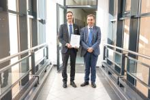 2 stehende Personen im Hauptgebäude der TUBAF - Apl. Prof. Patrick Gehre mit Urkunde in der Hand (links) und Prof. Christos G. Aneziris (rechts)